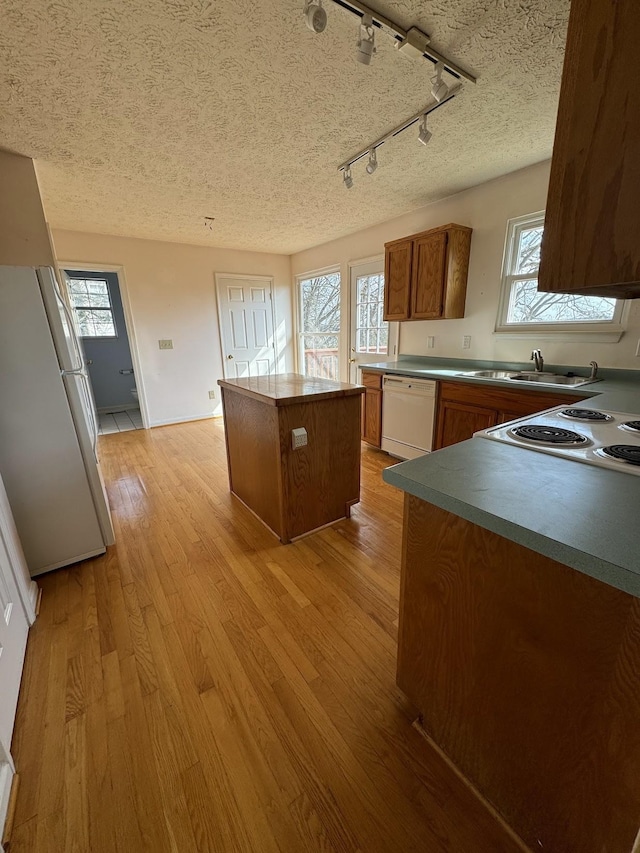 kitchen featuring light hardwood / wood-style floors, a healthy amount of sunlight, white appliances, track lighting, and a kitchen island