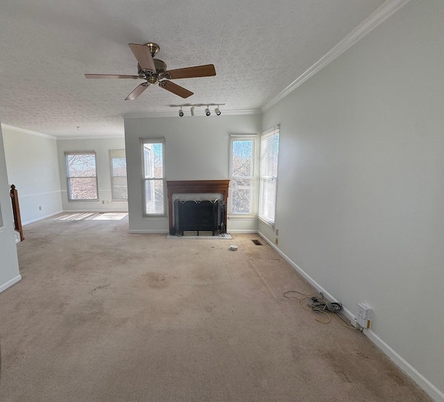 unfurnished living room with a textured ceiling, track lighting, ornamental molding, ceiling fan, and light colored carpet