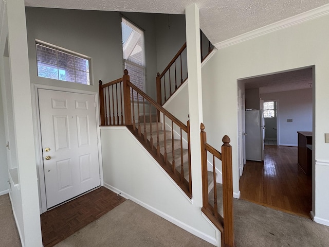 carpeted entryway with a textured ceiling and ornamental molding