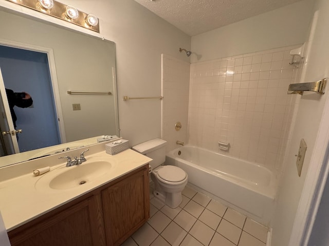 full bathroom featuring a textured ceiling, tiled shower / bath, tile patterned floors, vanity, and toilet