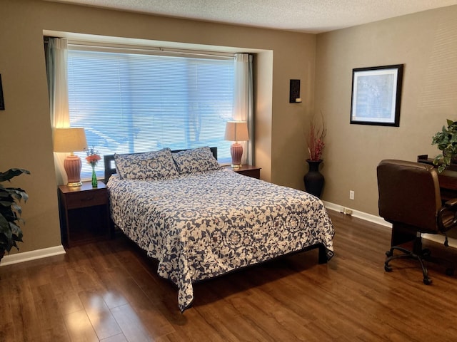 bedroom with multiple windows, dark hardwood / wood-style floors, and a textured ceiling