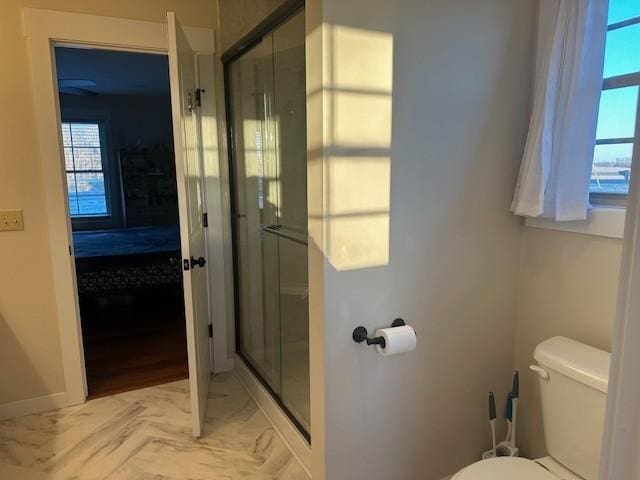 bathroom featuring a shower with shower door and toilet