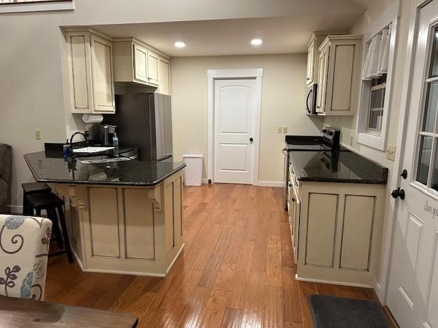 kitchen featuring kitchen peninsula, appliances with stainless steel finishes, a kitchen breakfast bar, and cream cabinets