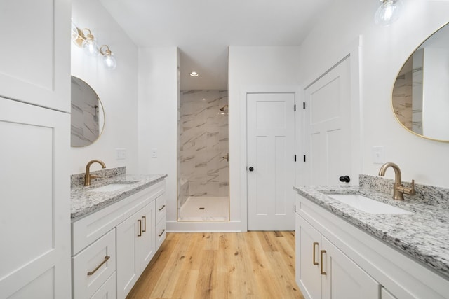 bathroom featuring vanity, wood-type flooring, and a tile shower