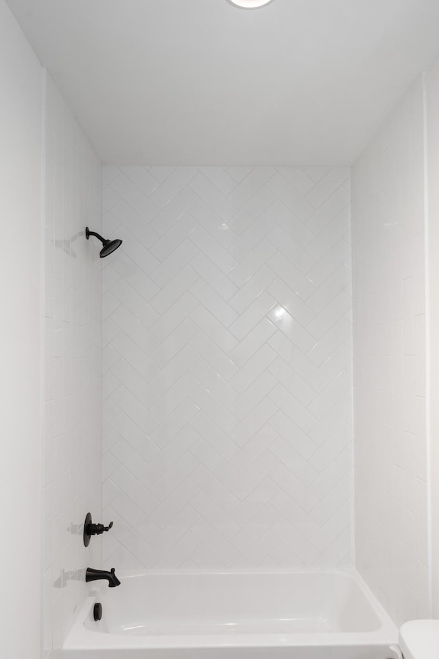 bathroom featuring toilet and tiled shower / bath combo