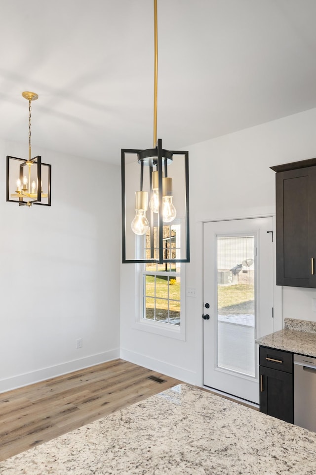 unfurnished dining area with an inviting chandelier and light wood-type flooring