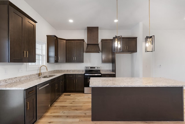 kitchen with premium range hood, sink, hanging light fixtures, light stone countertops, and appliances with stainless steel finishes