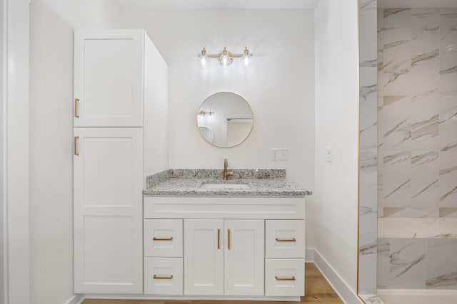 bathroom featuring a tile shower, wood-type flooring, and vanity