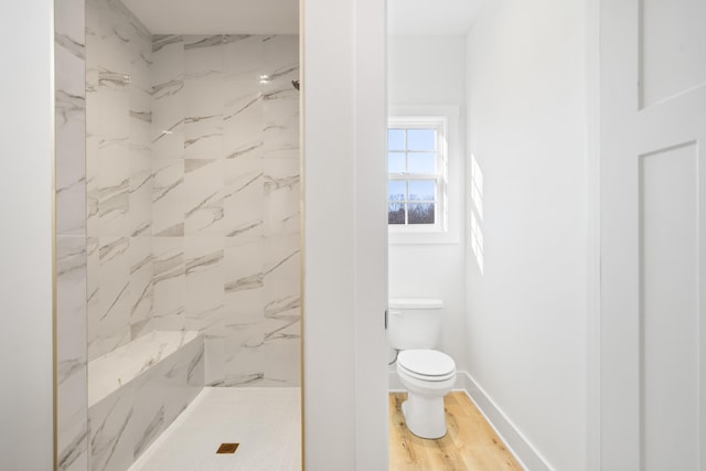 bathroom featuring toilet, wood-type flooring, and tiled shower