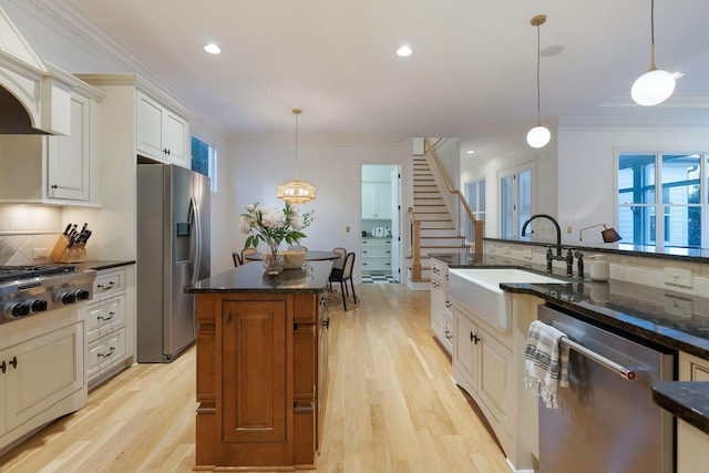 kitchen with stainless steel appliances, dark stone countertops, sink, backsplash, and hanging light fixtures