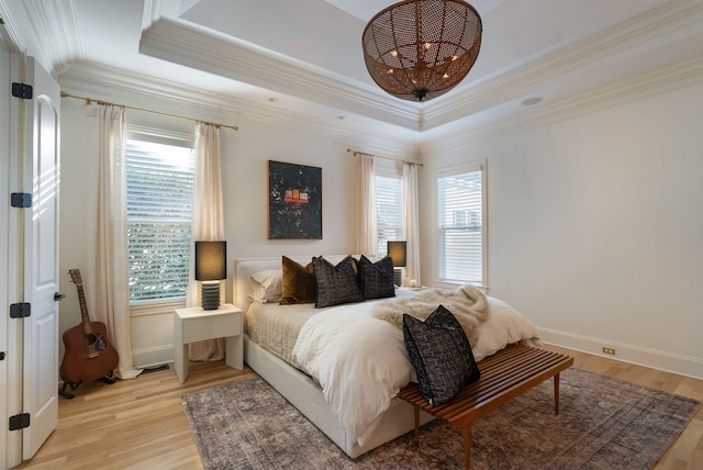 bedroom with a tray ceiling, ornamental molding, and light wood-type flooring