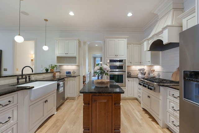 kitchen with decorative light fixtures, backsplash, a center island, white cabinetry, and appliances with stainless steel finishes