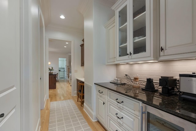 bar with white cabinetry, beverage cooler, and ornamental molding