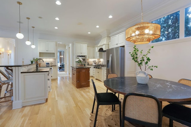 dining space with light hardwood / wood-style floors, sink, and crown molding