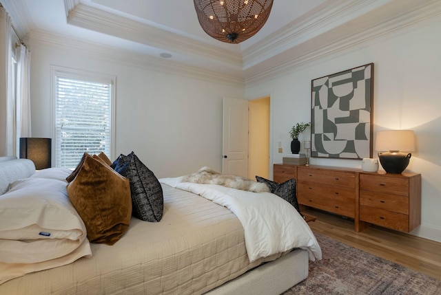 bedroom with wood-type flooring, a tray ceiling, and crown molding