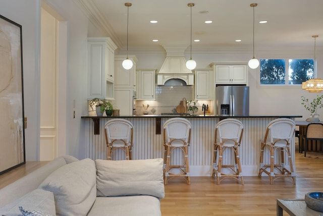 interior space with stainless steel fridge with ice dispenser, a breakfast bar area, pendant lighting, and backsplash