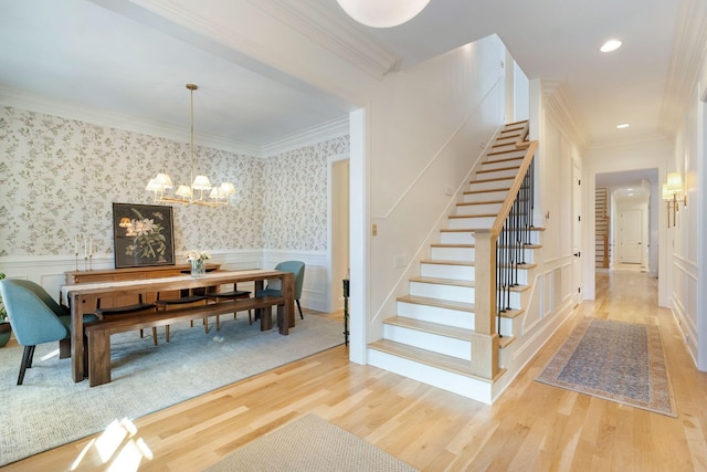 dining room featuring light wood-type flooring, a notable chandelier, and crown molding