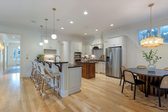 kitchen featuring white cabinets, appliances with stainless steel finishes, an inviting chandelier, and pendant lighting