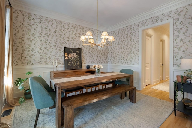 dining area with light hardwood / wood-style flooring, crown molding, and an inviting chandelier