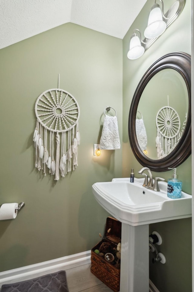 bathroom featuring hardwood / wood-style flooring, sink, a textured ceiling, and lofted ceiling