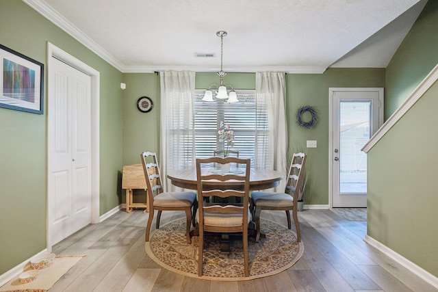 dining room with a chandelier, light hardwood / wood-style flooring, and crown molding