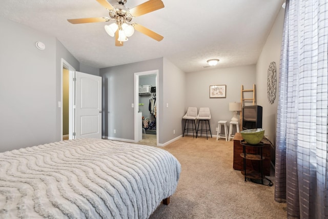 carpeted bedroom featuring ceiling fan, a textured ceiling, a closet, and a walk in closet