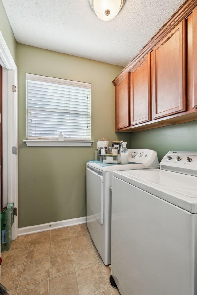 clothes washing area featuring cabinets, a textured ceiling, independent washer and dryer, and light tile patterned flooring