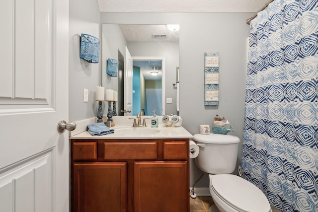 bathroom with a textured ceiling, toilet, vanity, and tile patterned flooring