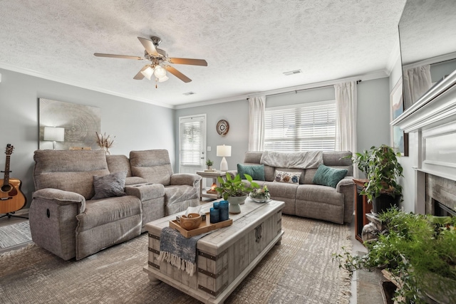 living room with a tile fireplace, a textured ceiling, and crown molding