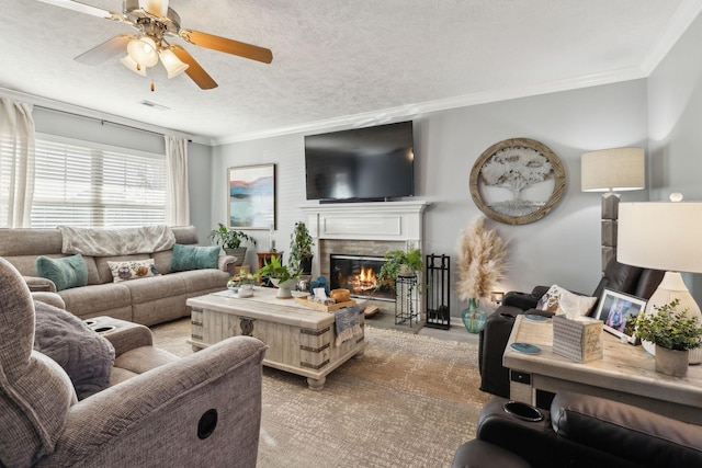 living room with crown molding, a tile fireplace, a textured ceiling, and ceiling fan