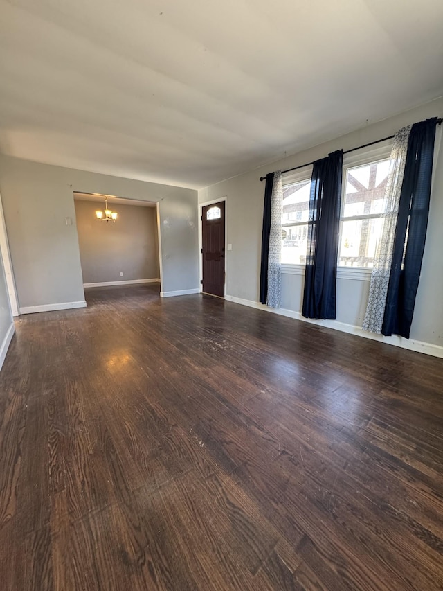 spare room with dark wood-type flooring and a chandelier