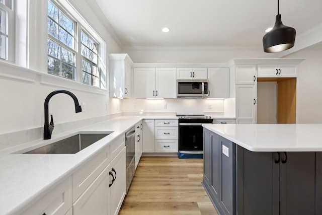 kitchen featuring stainless steel appliances, white cabinetry, sink, and pendant lighting