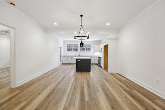 kitchen with light wood-style flooring, a kitchen island, baseboards, light countertops, and crown molding