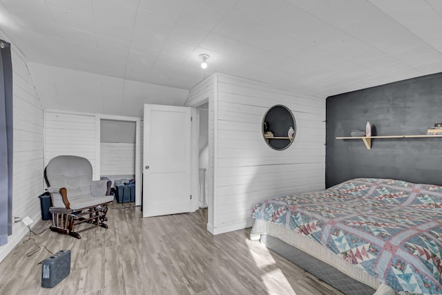 bedroom with wood-type flooring and wooden walls