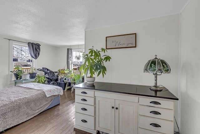 bedroom with crown molding, hardwood / wood-style flooring, and a textured ceiling