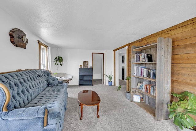 living room with carpet, wood walls, and a textured ceiling