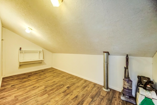 bonus room with lofted ceiling, hardwood / wood-style floors, and a textured ceiling