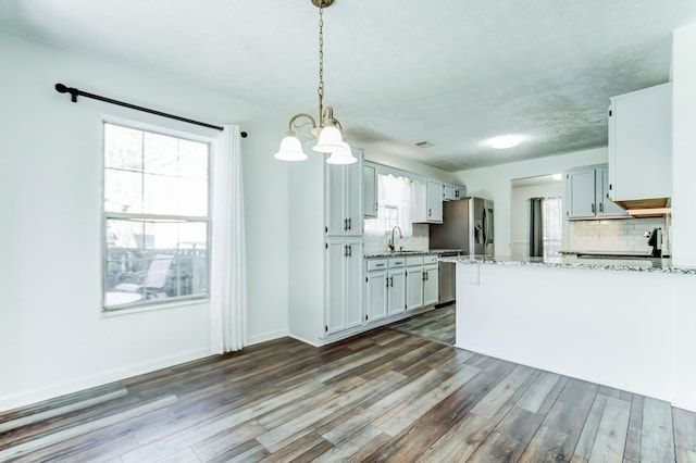 kitchen with pendant lighting, white cabinetry, backsplash, light stone counters, and stainless steel refrigerator with ice dispenser