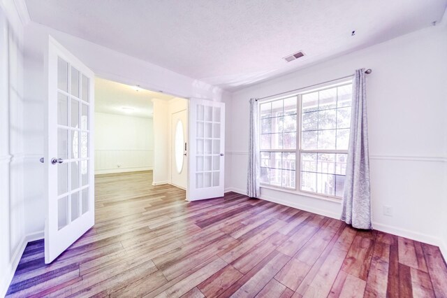 empty room with light hardwood / wood-style flooring and french doors