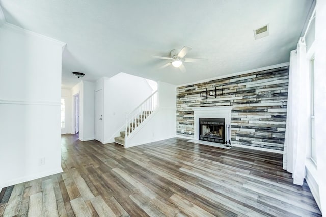 unfurnished living room with hardwood / wood-style flooring, ceiling fan, ornamental molding, and a fireplace