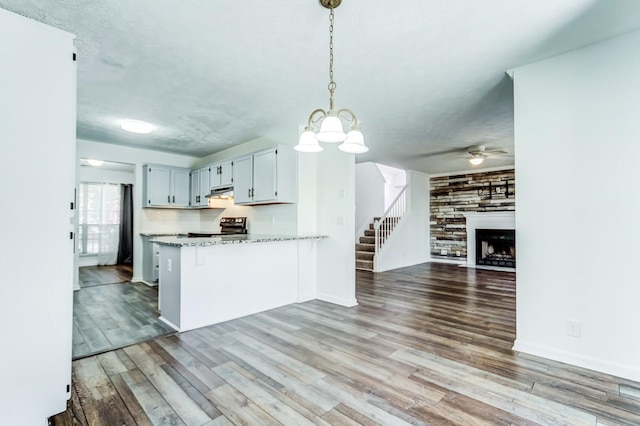 kitchen featuring hanging light fixtures, wood-type flooring, a breakfast bar, and kitchen peninsula