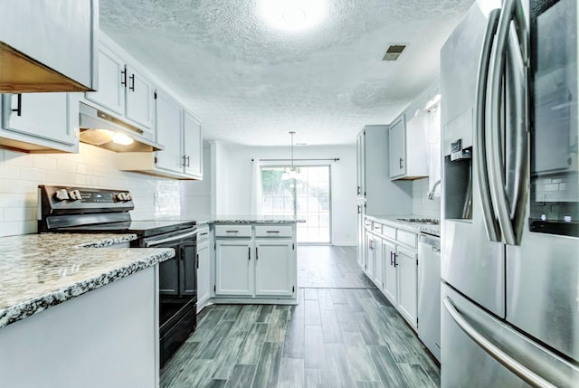 kitchen featuring wood-type flooring, decorative light fixtures, stainless steel appliances, light stone countertops, and white cabinets