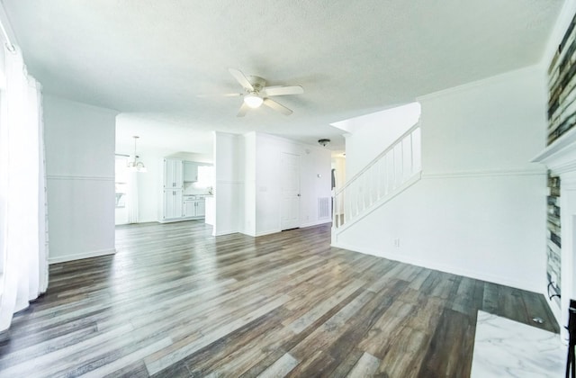 unfurnished living room featuring dark wood-type flooring, a textured ceiling, and ceiling fan