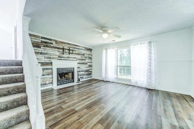 unfurnished living room with ceiling fan, a fireplace, and wood-type flooring