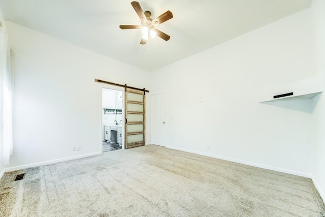 spare room with sink, carpet floors, a barn door, and ceiling fan