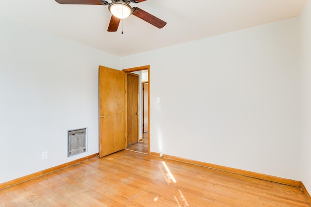 empty room with heating unit, wood-type flooring, and ceiling fan