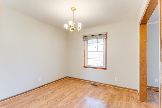 unfurnished room with a notable chandelier and light hardwood / wood-style flooring