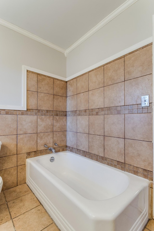 bathroom with toilet, crown molding, a tub, and tile walls