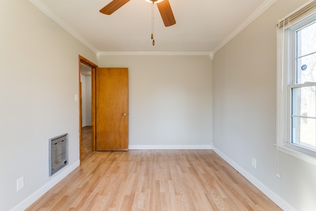 spare room with light wood-type flooring, ornamental molding, heating unit, and plenty of natural light