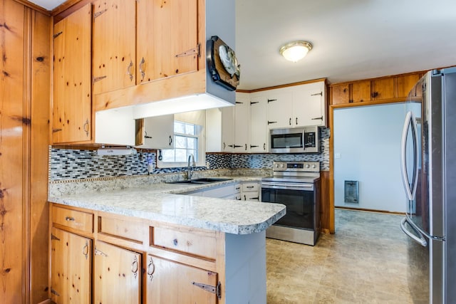 kitchen featuring backsplash, kitchen peninsula, sink, stainless steel appliances, and white cabinets